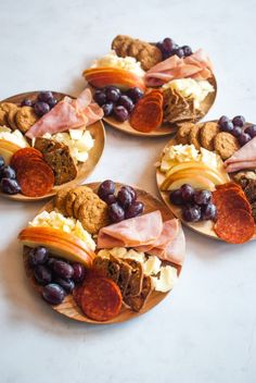 four wooden plates filled with different types of food on top of a white countertop