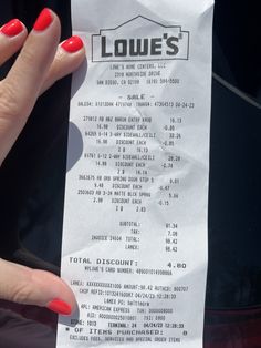 a woman's hand with red nails holding up a paper receipt that reads lowe's