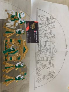 some gold and green decorations on top of a piece of paper next to a drawing