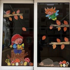 there are two windows decorated with cartoon characters in the window sill, and one has fallen leaves on it