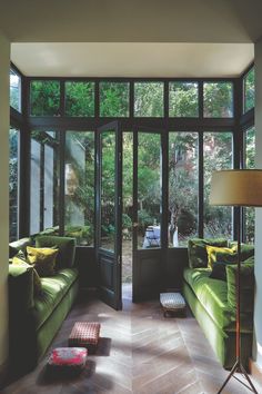 a living room filled with green furniture and lots of glass doors that open up to the outside