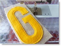 a sewing machine is next to a yellow felt with the letter c on it's side