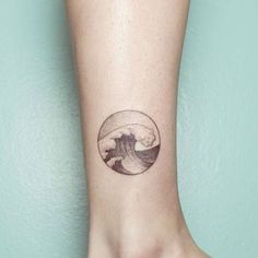 a small tattoo on the ankle of a person with a wave coming out of it