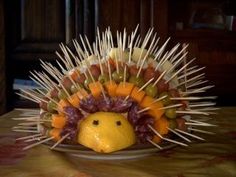 a hedgehog made out of fruits and vegetables on a plate with spikes sticking out of it's head