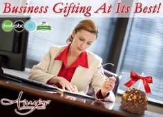 a woman sitting at a desk writing on a piece of paper with the words business gifting at its best