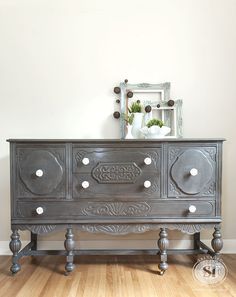 an old dresser is painted gray with white knobs