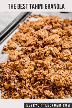 granola on a baking sheet with two black spoons