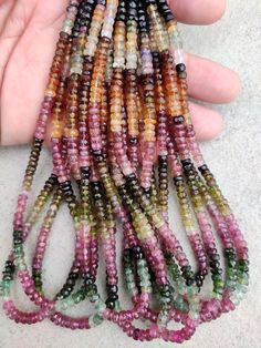 a hand holding several multicolored beads