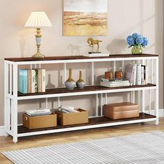 a white shelf with books and vases sitting on top of it next to a lamp