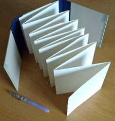 an open book sitting on top of a wooden table next to a pen