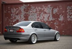 a silver car parked in front of a brick wall