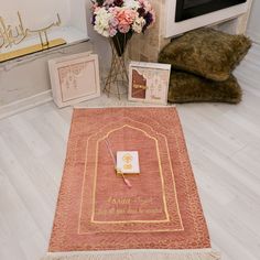 a living room with a rug, flowers and pictures on the floor in front of a fireplace