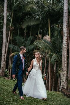 a bride and groom holding hands in front of palm trees