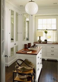 a kitchen with white cabinets and wooden counter tops next to a door that leads to another room