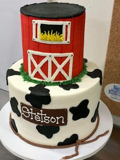 a red and white cake decorated with black and white cow print on the side, along with a fire place