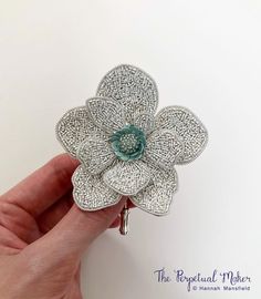 a person holding a flower brooch in their hand