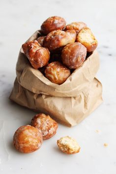 a bag full of doughnuts sitting on top of a white counter next to some pieces of bread