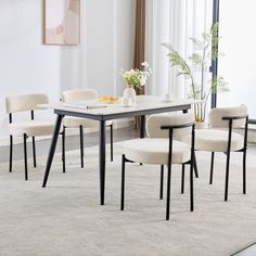 a dining room table with four chairs and a vase filled with flowers on top of it