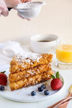 a person is sprinkling sugar on some desserts with berries and strawberries