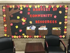 a bulletin board with fall leaves on it in front of two chairs and a table