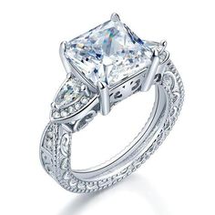 a princess cut diamond engagement ring with side stones on the band and an intricate filigree