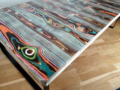 a table that has been painted with different colors and designs on it, sitting on a hard wood floor