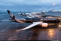 an air new zealand plane parked at the airport terminal with other planes in the background