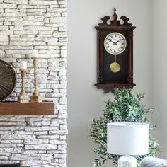 a clock mounted to the side of a brick wall next to a lamp and table