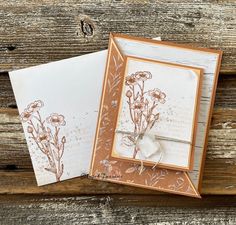 two cards with flowers on them sitting next to each other in front of a wooden background