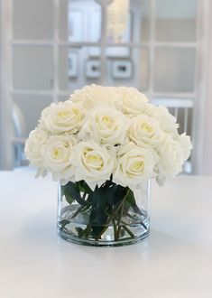 a vase filled with white roses on top of a table