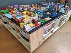 a table with legos on it in the middle of a room filled with other toys