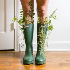 a person wearing green rain boots with plants growing out of them