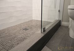 a white toilet sitting next to a walk in shower under a glass door on the side of a wall