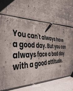 a man walking down the sidewalk next to a wall with a quote on it that says, you can't always have a good day but you can always face a bad day with a bad day with a good attitude