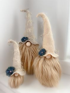 two stuffed gnomes with long blonde hair and blue flowers on their heads are sitting next to each other