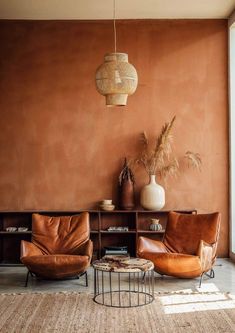 a living room with two leather chairs and a coffee table in front of an orange wall