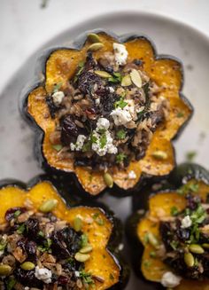 four stuffed acorns on a plate topped with nuts and feta cheese