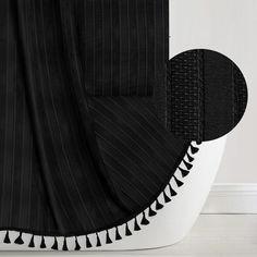 a black and white striped curtain with tassels on the bottom, next to a round hole in the middle