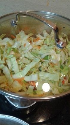 a pan filled with cabbage and carrots on top of a stove