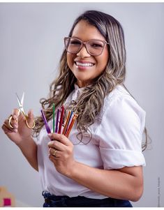 a woman in glasses holding scissors and colored pencils