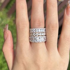 a woman's hand with three wedding bands on her fingers and two diamond rings in the middle