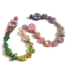 three bracelets with different colored beads and charms on white background, close up photo