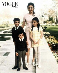 a woman and two children posing for a photo in front of some flowers on the sidewalk