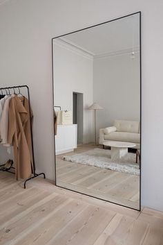 a large mirror sitting on top of a hard wood floor next to a white couch