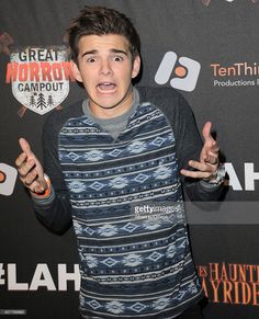 a young man with his hands in the air while standing on a red carpet at an event