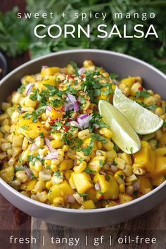 a bowl filled with corn and garnished with cilantro, lime wedges