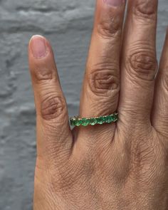 a person's hand with a green ring on it