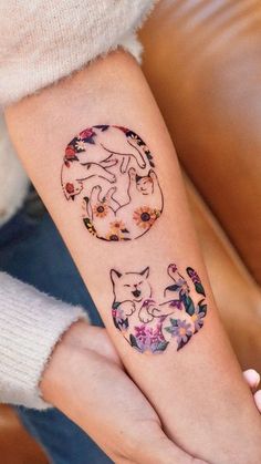 a woman's arm with two cats on it and flowers around the wrist tattoo