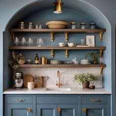 a kitchen with blue cabinets and gold trim on the upper half of the cabinet, along with brass pulls