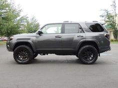 a gray toyota 4runner is parked in a parking lot next to some trees and bushes